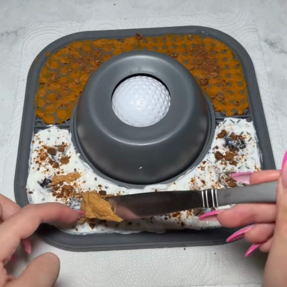 Person using a knife to spread something on a textured surface with a central circular object.